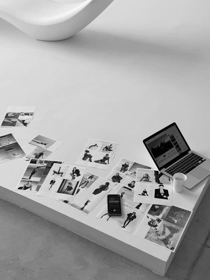 Printed brand photos spread across a desk beside a laptop